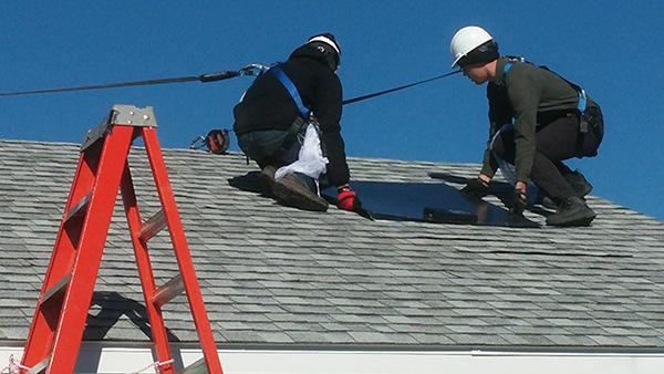 Installers place SunShot panel on a roof