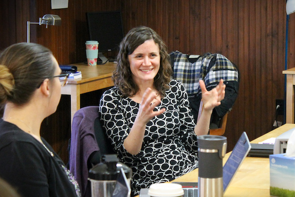 Food and Agriculture Clinic Director Sophia Kruszewski smiles while explaining a concept to students sitting around a table.